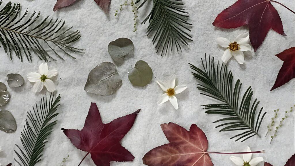 Tejidos de ecoprint con hojas naturales y flores sobre fondo claro